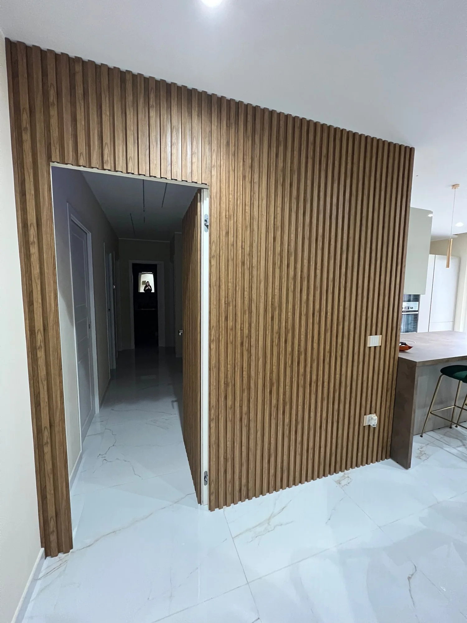 Parete rivestita con listelli in legno intorno al passaggio verso il corridoio.
