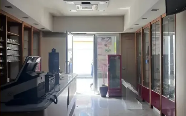 Fotografia del negozio prima dei lavori, con vetrine in legno scuro e banco esistente.